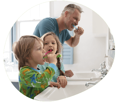 Father and children brushing teeth together