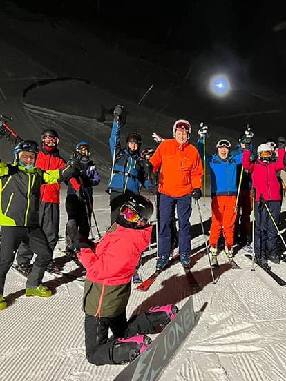 A group of Denplan dentists cheering on a ski slope at night time