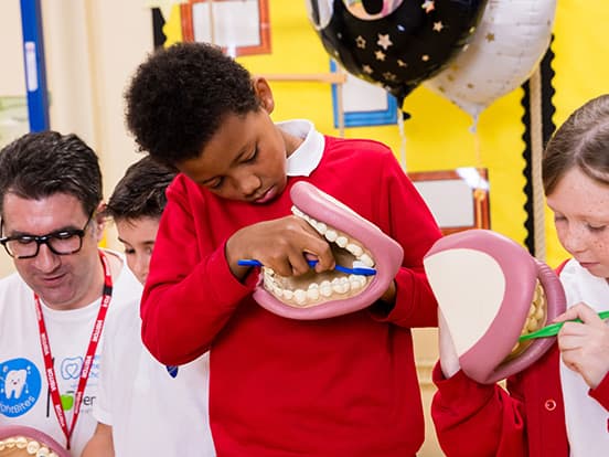 Children learning dental hygiene by brushing large mouth models