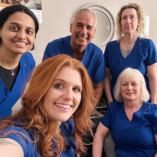 Oakhouse Dental Practice Team in blue scrubs pose for a group photo.