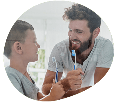 Father and son smiling and brushing teeth together