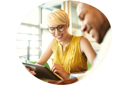 Two colleagues smiling and looking at an iPad