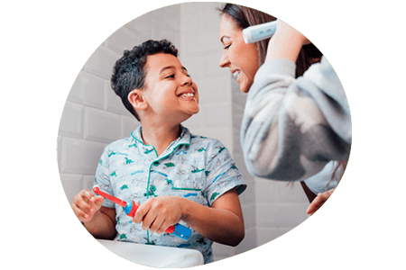 Mother and child brushing teeth together and smiling