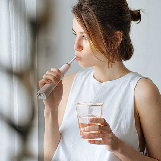 Lady brushing her teeth looking out window