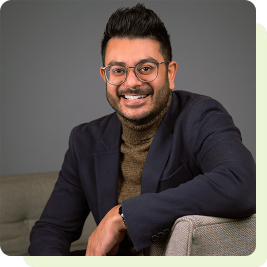 Dentist Shamir sitting on sofa and smiling