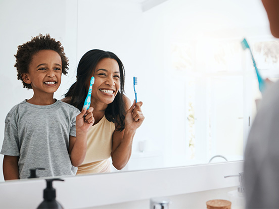 Mother and son with toothbrushes checking teeth in mirror