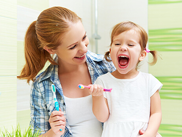 Morther helping young daughter brush their teeth