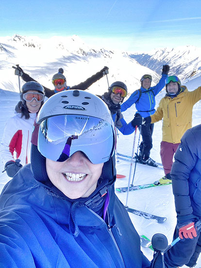 A group of Denplan dentits smiling with their hands in the air on a ski slope