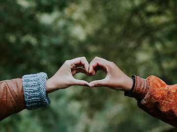 Two people making a heart shape with their hands